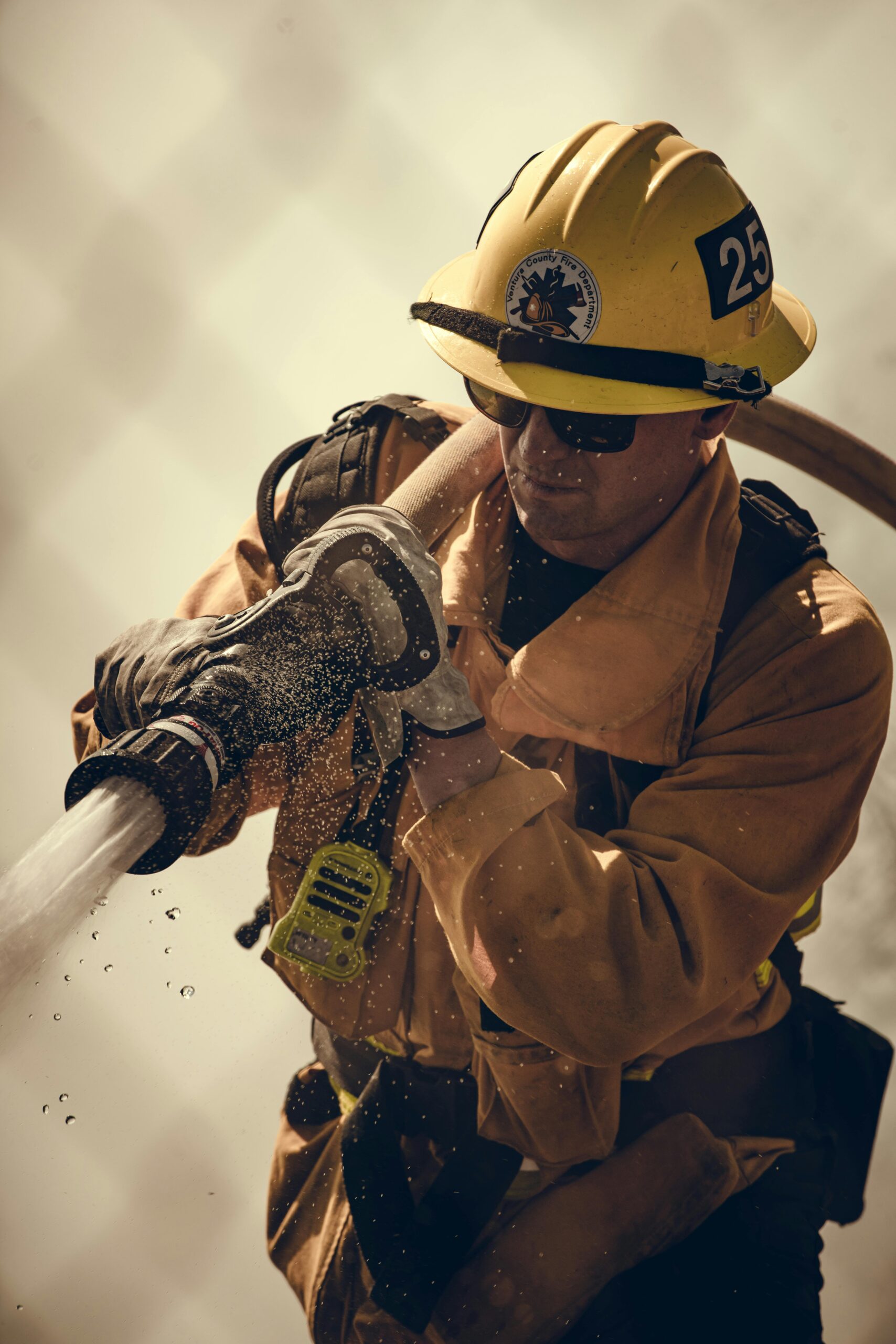 Firefighter equipped with protective gear sprays water during an emergency response.